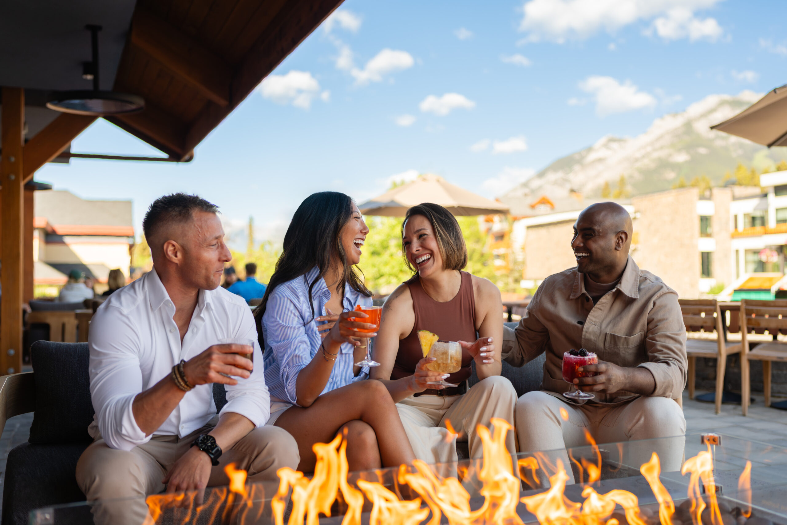 Two couples enjoying cocktails on Good Folk's patio in front of a fire pit.