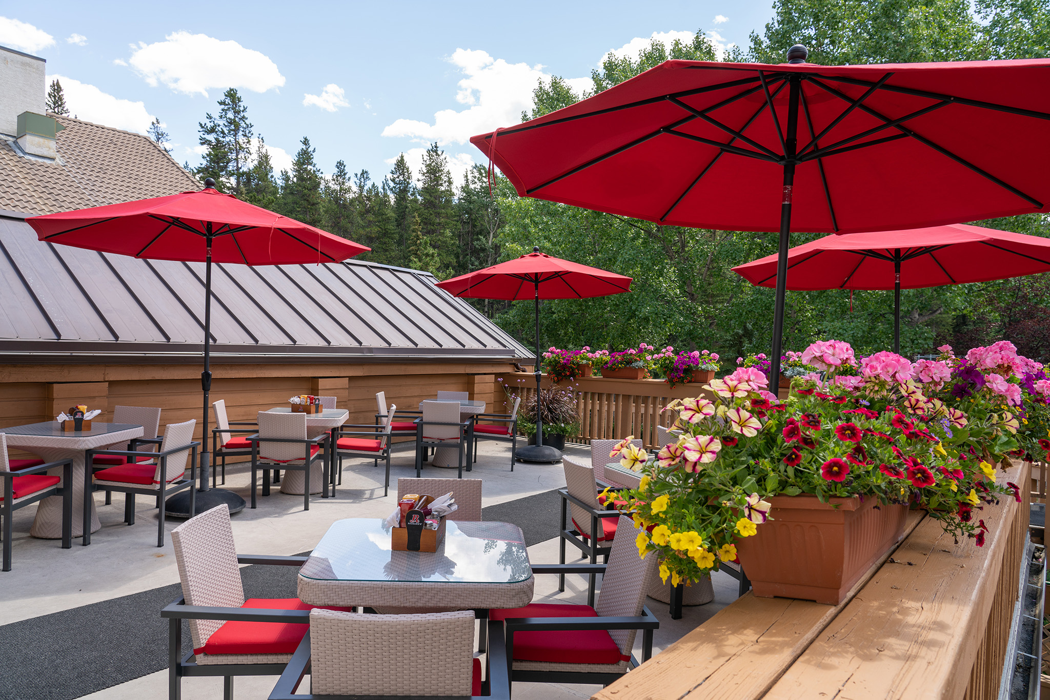 Alpha Bistro patio with flowers and red umbrellas